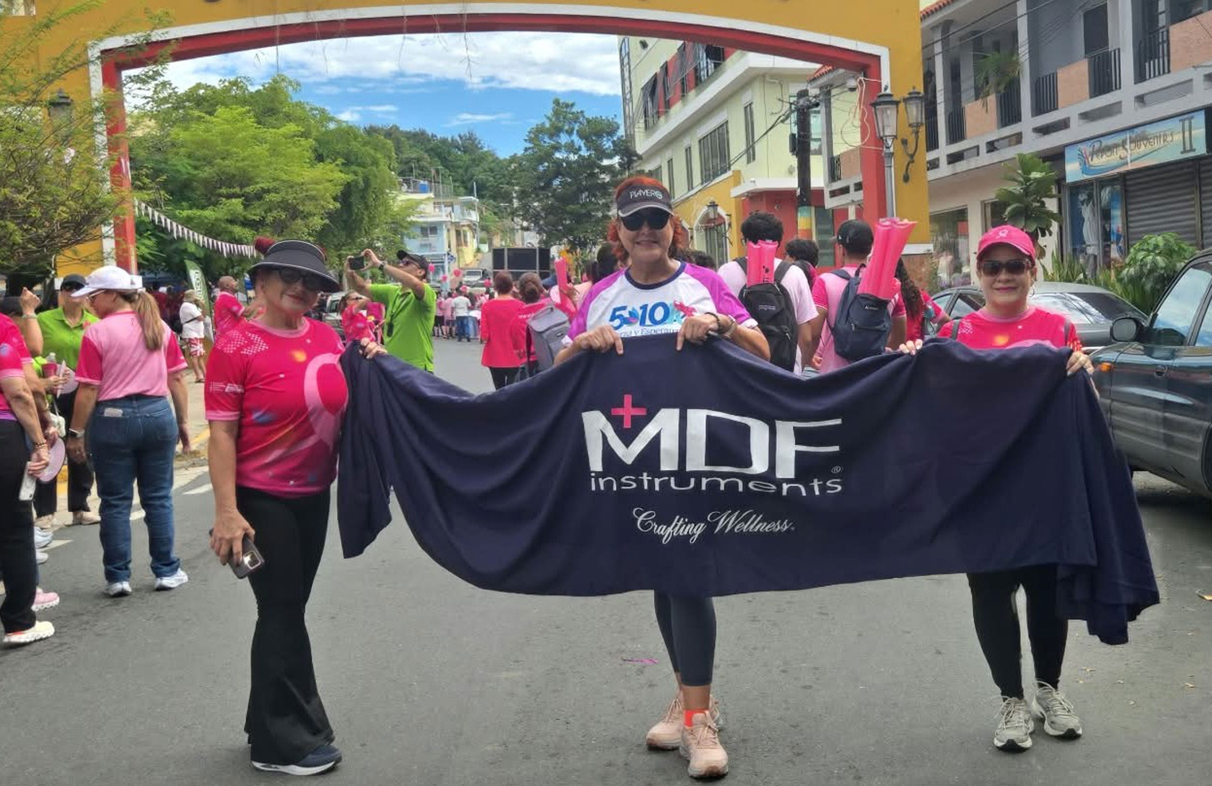Participants hold an MDF Instruments Crafting Wellness banner at the 2026 “Hazlo Por Ti” Breast Cancer Awareness March in Rincón, Puerto Rico.